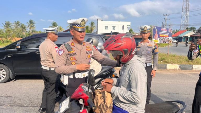 Personel Satlantas Polres Bintan membagikan takjil kepada pengendara di Bundaran Km 16 Toapaya